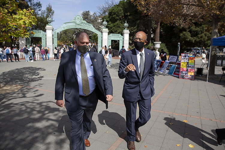 drake talks with steve sutton as they walk across sproul plaza near sather gate