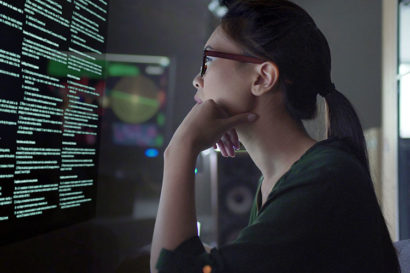 A photo of a woman looking at a computer screen that is filled with words.