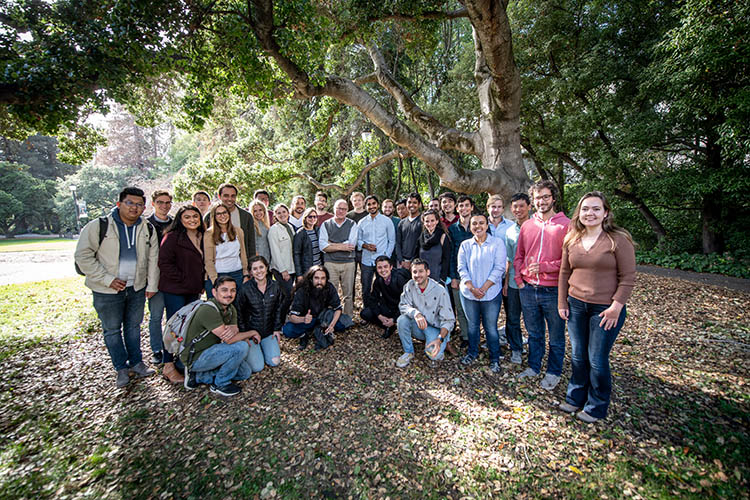 card poses with a large group of people under a tree