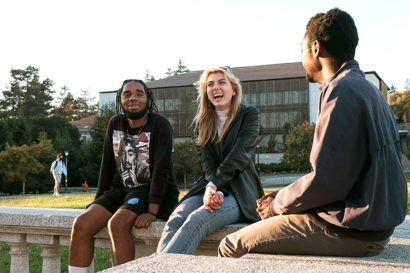 three students sit together talking