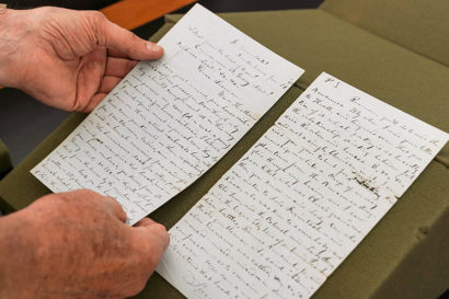 hands hold a page of a letter written by mark twain in 1861