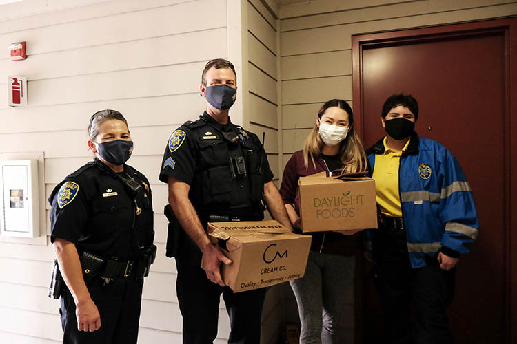 a group in masks stands holding boxes