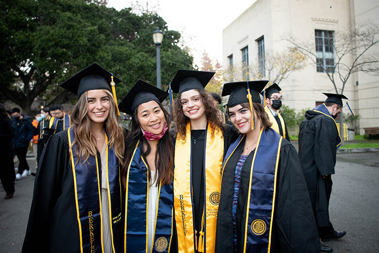 four women graduates stand together on graduation day