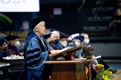 carol christ in graduation regalias speaks at a podium