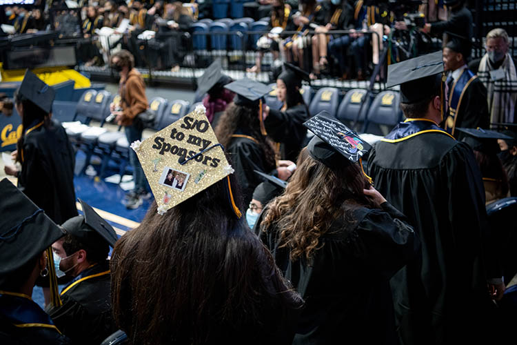 a graduate wears a hat that says 