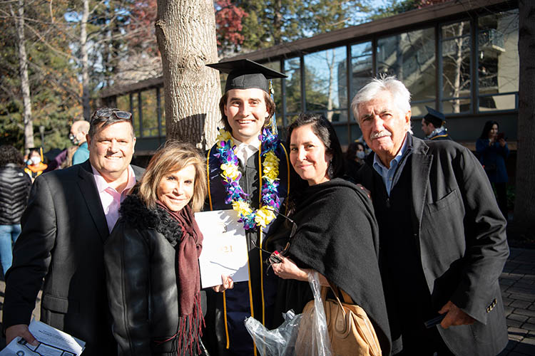 a graduate stands with four other people outside of the graduation venue