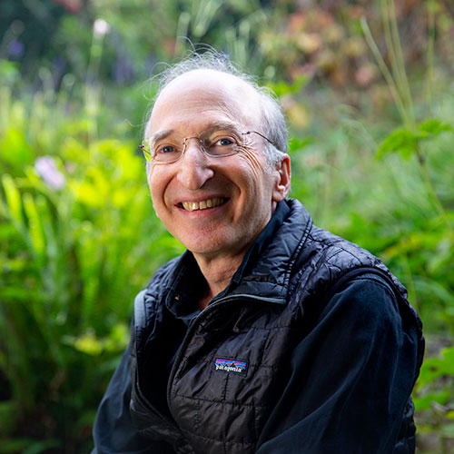 A photo of Saul Perlmutter against a leafy background.