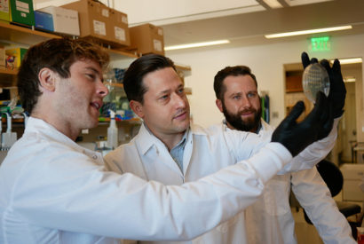 three male researchers looking at a petri dish