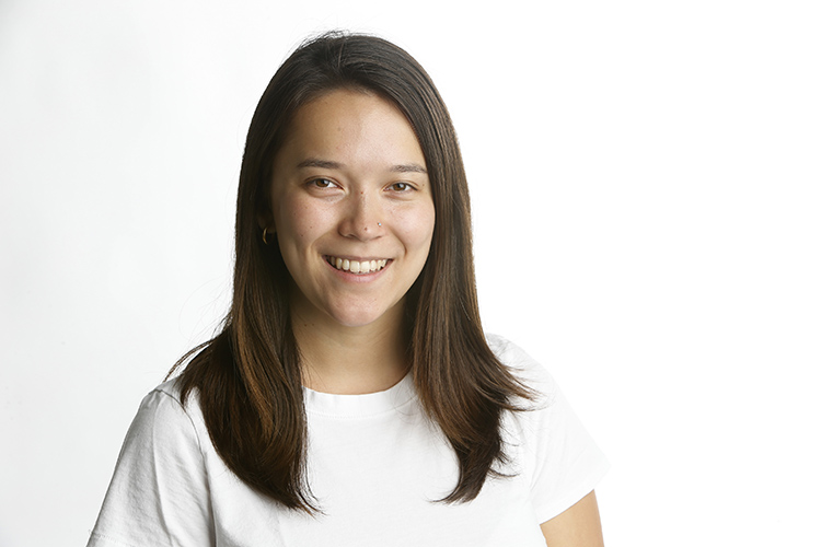 Haley Willis, a 2019 UC Berkeley graduate now at the New York Times, is wearing a white top and smiling at the camera in this portrait taken by a New York Times photographer