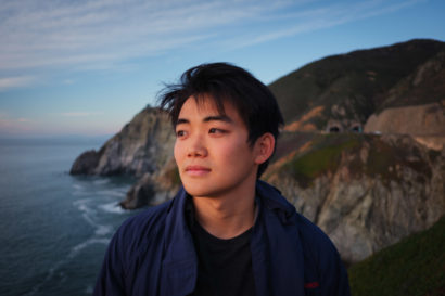 Kori Suzuki headshot with ocean and cliffs in the background.