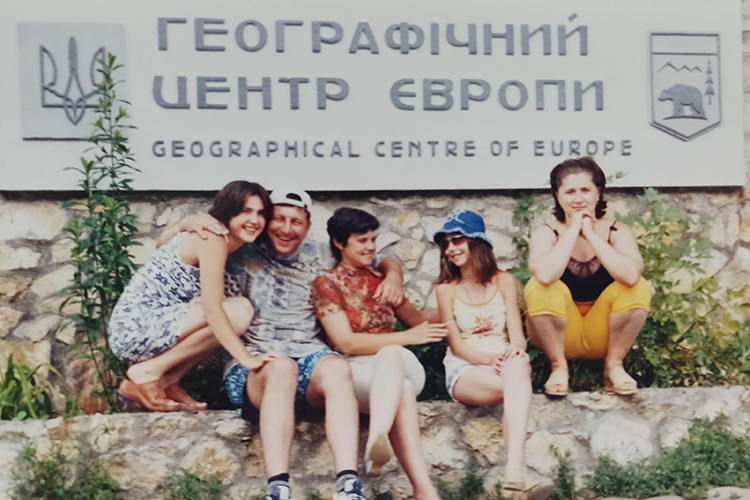 people smiling and hugging on a ledge in front of a building