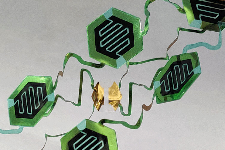 An image shows green electrical sensors connected by shiny ribbons