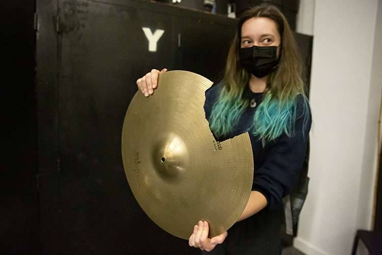 A student in the Cal Band hold a broken cymbal that can't be repaired. It has a huge chunk missing.