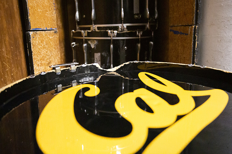 A Cal Band bass drum, with the campus's blue and gold lettering on it, is badly chipped and needs repair.