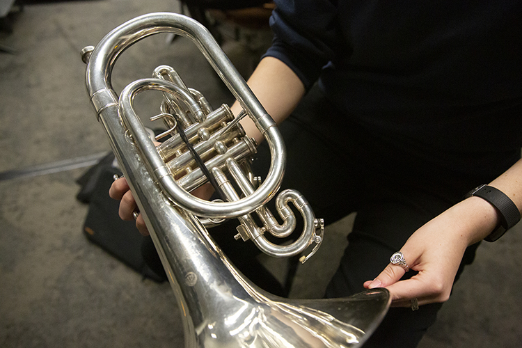 A black hair tie is used to hold parts of this silver-toned Cal Band baritone together.