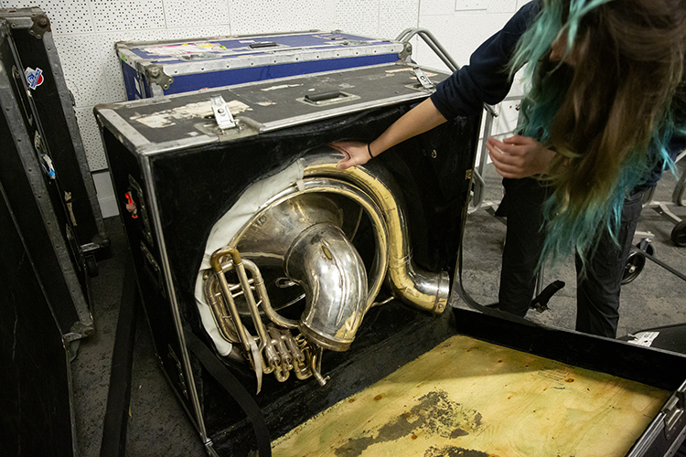 A Cal Band sousaphone is old and worn, and it's in an old and worn case, where the padding is coming off and shedding onto the instrument.