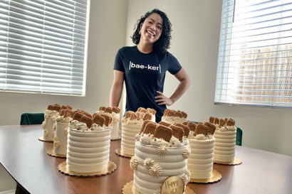 Yuki Burton posing with cakes on a table.