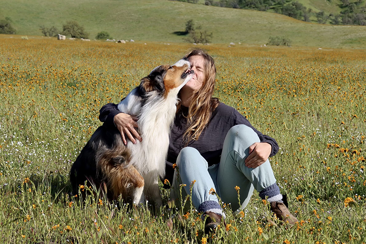 a person hugs her dog in a field