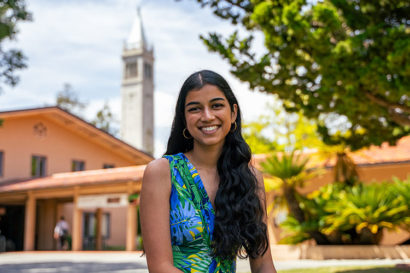 Anjika Pai, the 2022 top graduating senior, sits on campus with the campanile in the background.