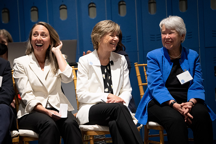 Three women sitting down laughing.