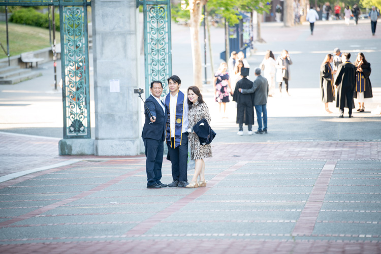 student takes a selfie near sather gate