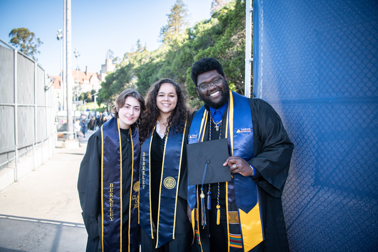 three students celebrate their graduation smiling