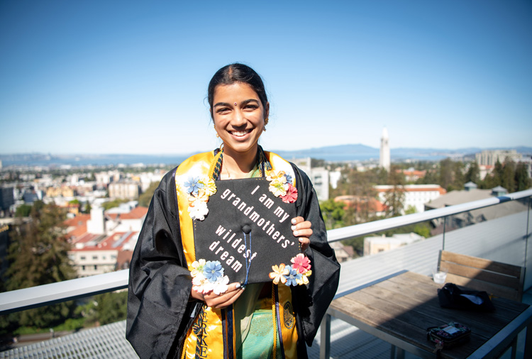 a woman holds a grad cap saying 