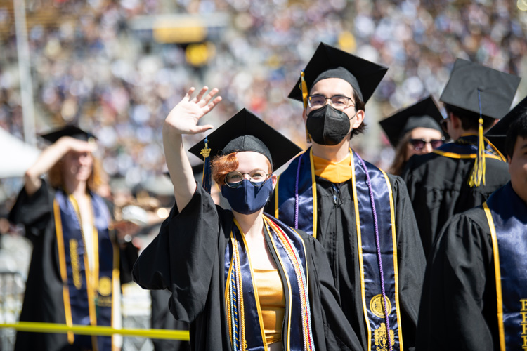 students in masks wave during graduation