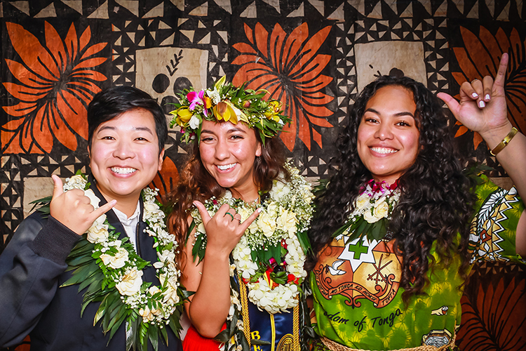 Three Berkeley co-workers in the Asian Pacific American Student Development office, wearing leis and smiling, celebrate the first in-person graduation ceremony for Pacific Islander students held since the pandemic began.