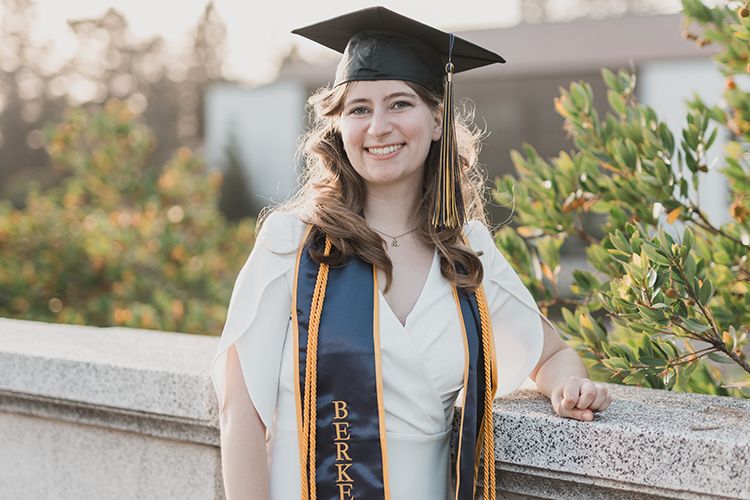 Meg Shriber, a recent alumna, poses in her cap and stole on campus.