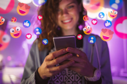 Young woman holding an electronic device with hearts and likes floating in the background.