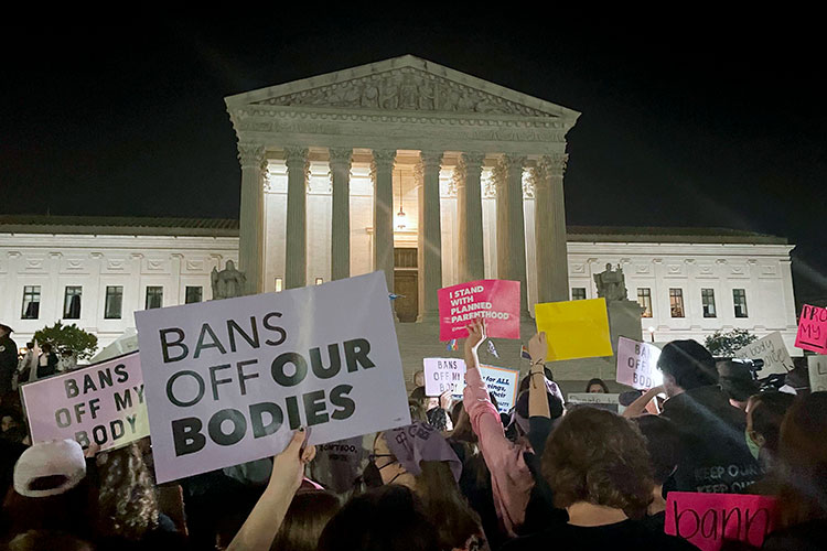 Pro-abortion protesters hold signs outside the US Supreme Court building in Washington, DC, the night the draft decision to overturn abortion rights was released.