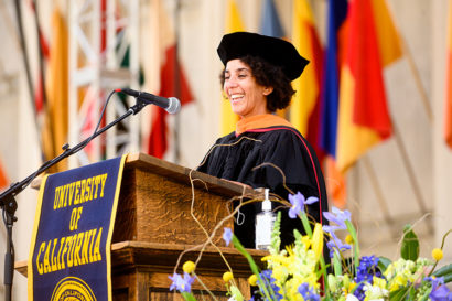 a person wearing a cap and gown speaks at a podium