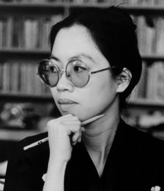 black and white photo of a person wearing round glasses and holding a pencil to her chin