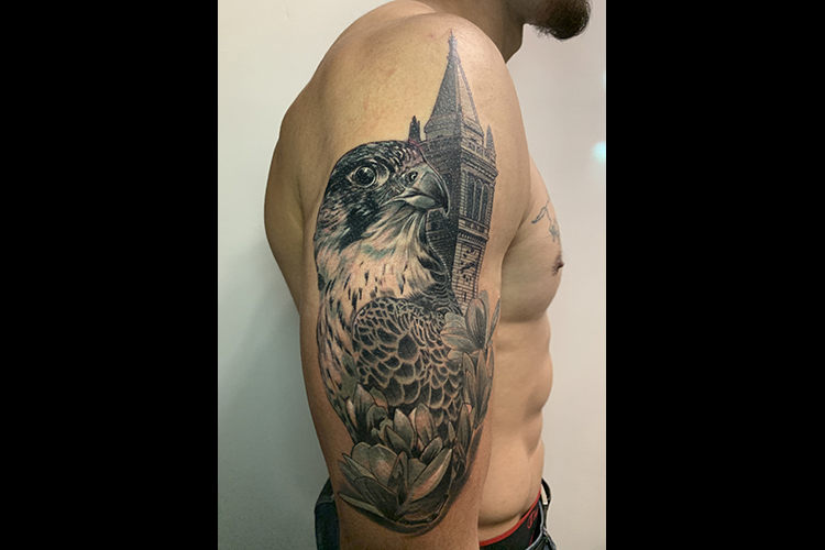 Jonny Hale, a Berkeley student, poses without his shirt on to show his right arm, where he has a large tattoo of a falcon, the Campanile and a branch of magnolia blossoms.