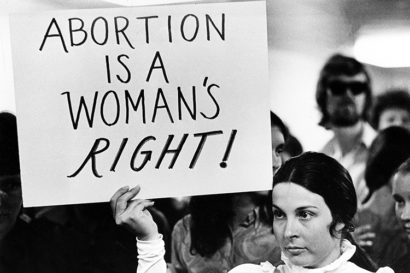 a person holds up a sign that reads "Abortion is a woman's right."