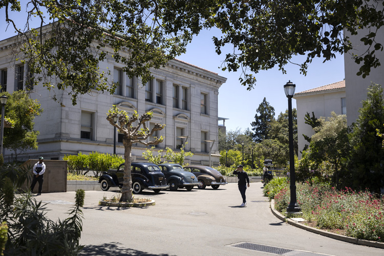 old cars and people walk on a sunny day on campus