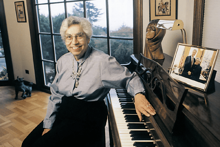 A photo of Joyce Lashof with her arm on a piano.