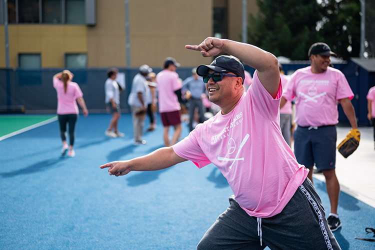 Glenn DeGuzman, director of Residential Life, smiles and gestures at his team from the sidelines at a Student Affairs Summer Softball League game.