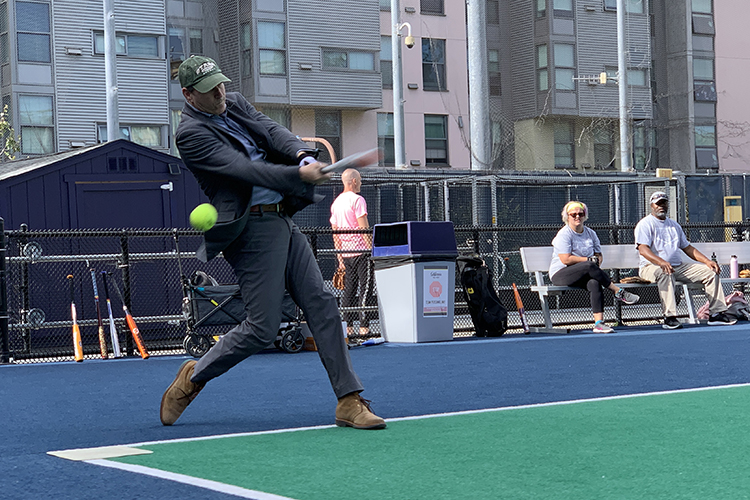 In a suit, Associate Vice Chancellor for University Health Services Guy Nicolette swings at a ball at