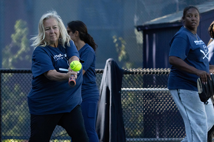 Susan Roach, a retired staffer in the Division of Student Affairs, takes a swing at the softball at a Student Affairs Summer Softball League game.