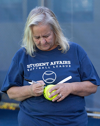 Susan Roach, a former administrator in the Division of Student Affairs, was an honoree at the first game of the Student Affairs Summer Softball League. In this photo, she's signing the ball.