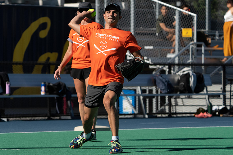 Jeremy Brooks and Sue Harbour from the Career Center, wearing their team's orange T-shirts, play softball during the 2022 Student Affairs Summer Softball League series for 2022.