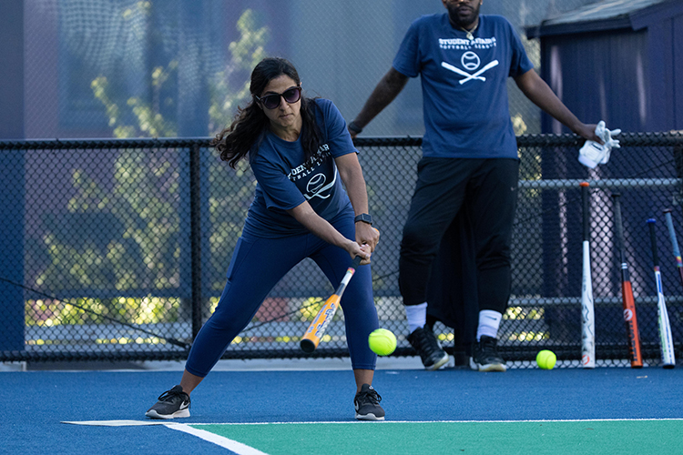 In her team's navy blue T-shirt, Bahar Navab, assistant vice chancellor and chief of staff for student affairs, swings at the ball while Yasin Id-Deen waits for his turn at bat.