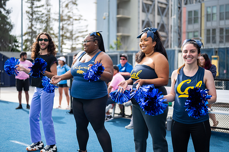 Wearing Cal gear and holding pom-poms, the Residential Life cheer squad gets the team pumped up at a Student Affairs Summer Softball League game.