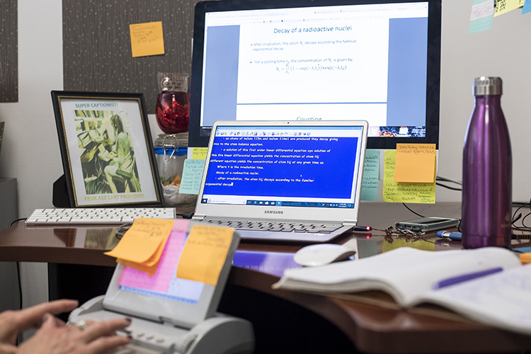 a person types at a computer screen, transcribing a written powerpoint slide about chemistry into a devices that will narrate what the slide says to those who can't easily see computer screens