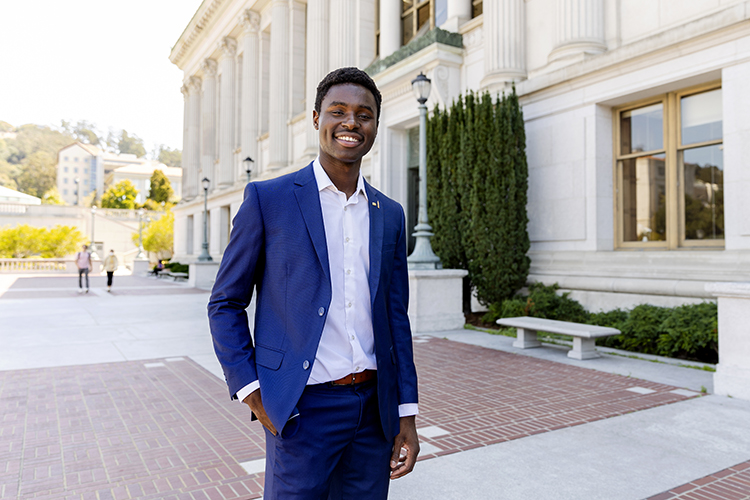 Chaka Tellem, ASUC president, poses for a photo outside California Hall wearing a bright blue suit and a white shirt.