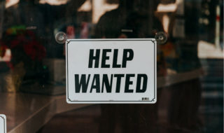 a Help Wanted sign on a glass door