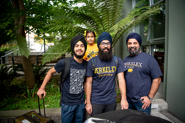 A family wearing Cal T-shirts stops to pose for the camera on during Move-in days 2022.