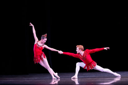 two ballet dancers wearing red dance on stage